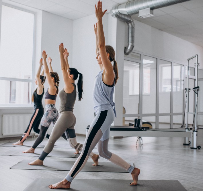 Gruppe von Frauen macht Yoga oder Pilates im Studio – Training für Beweglichkeit, Kraft und Balance.