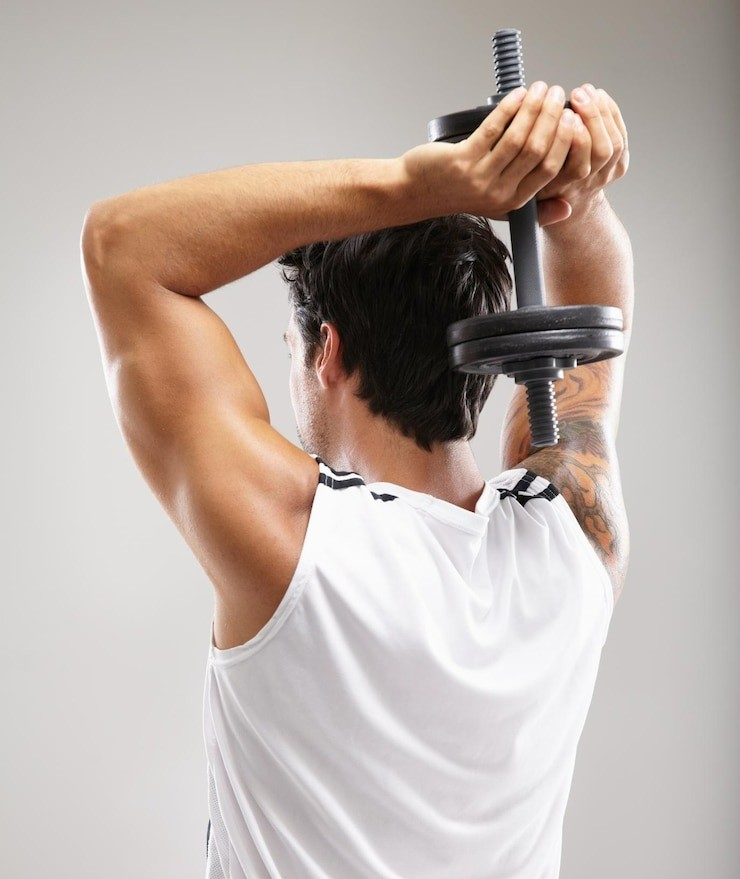 Mann führt ein Trizeps-Training mit einer Kurzhantel über dem Kopf aus – gezieltes Krafttraining für Arme und Schultern.